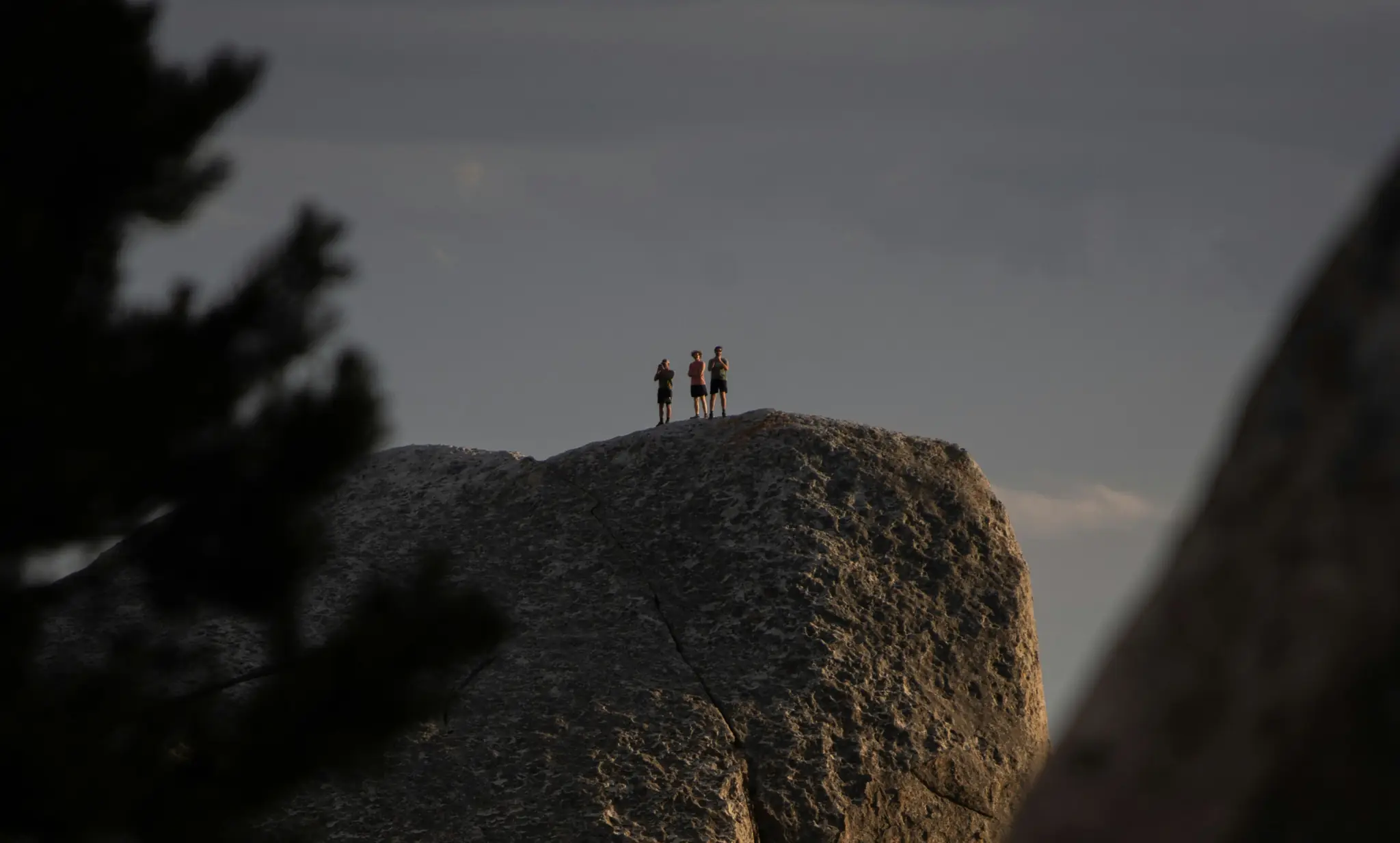 Three hikers standing on top of a boulder with Gaia GPS Hike mode layer toggles overlaid on the view