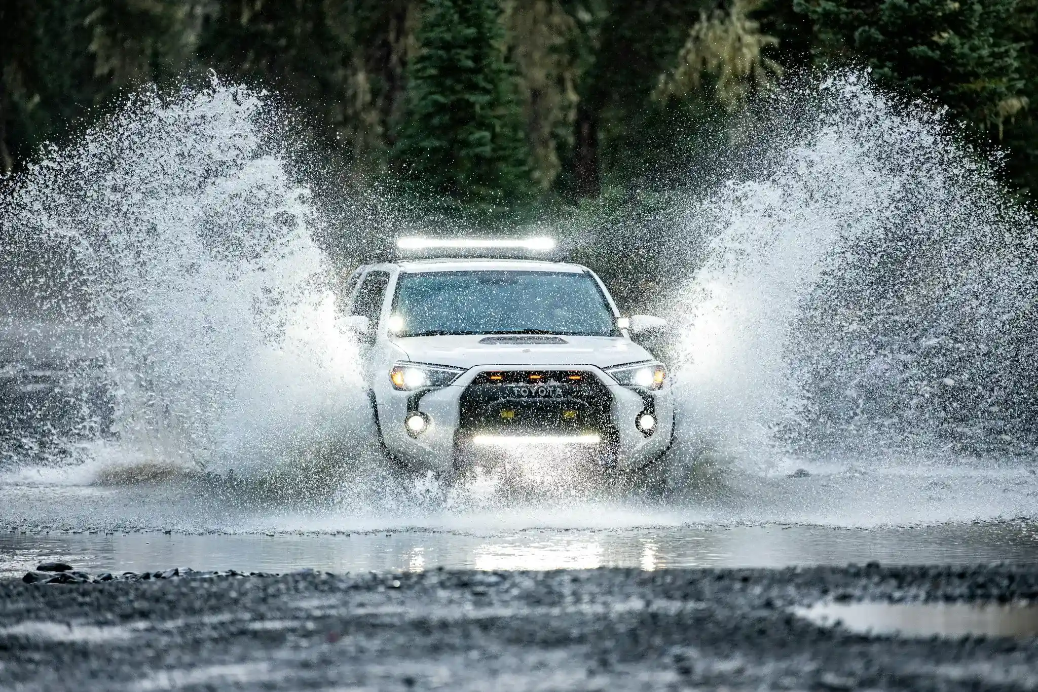 A rugged off-road vehicle fording a river with Gaia GPS Off-Road mode layer toggles overlaid on the view
