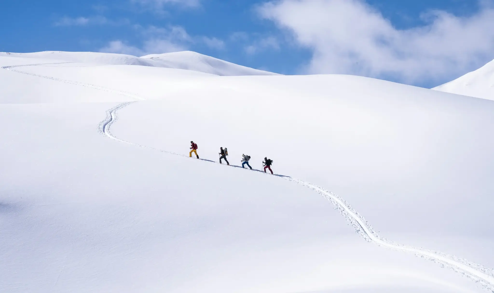 Four mountaineers crossing a snow field with Gaia GPS Snow mode layer toggles overlaid on the view
